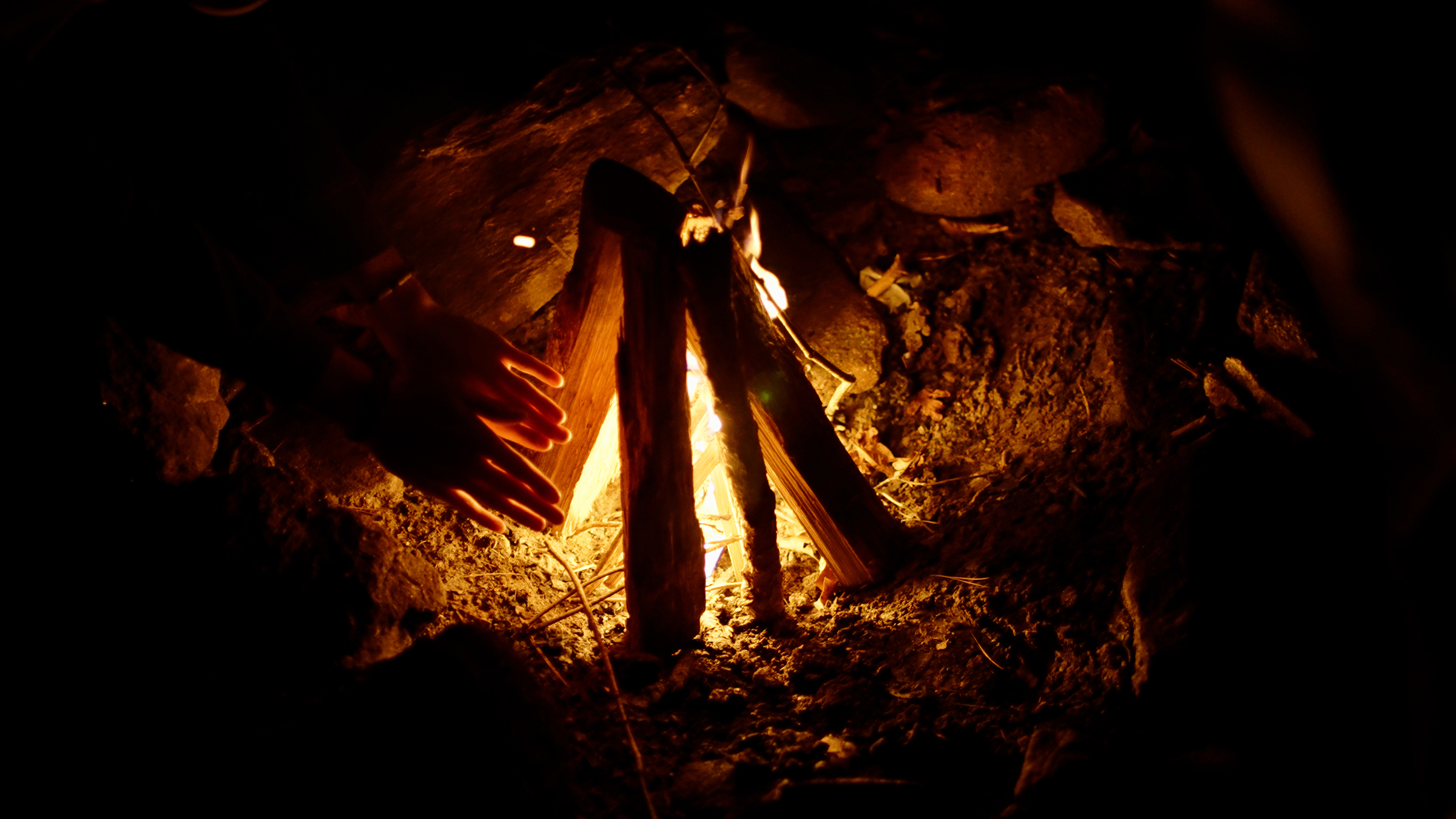 A shot of someone warming up their hands above the bonfire